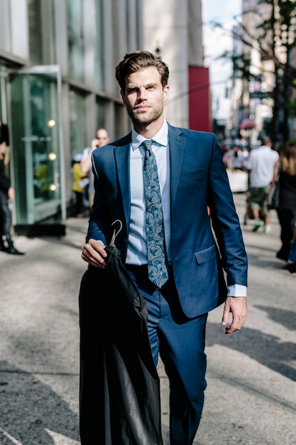 Bel homme d'affaires marchant à Manhattan, portant une veste sur un cintre