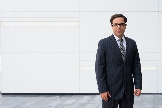 Bel homme d'affaires persan posant devant un mur blanc