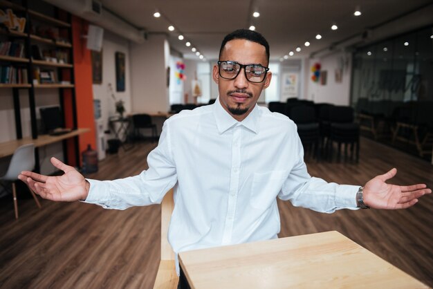 bel homme d'affaires portant des lunettes assis à la table et regardant à l'avant