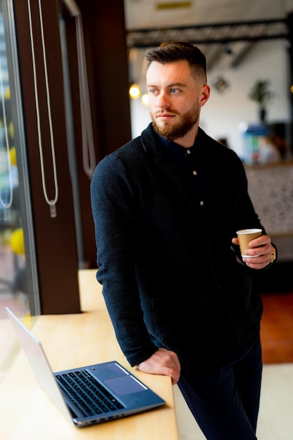 Bel homme d'affaires prospère assis dans le café Jeune homme confiant travaillant avec une tasse de café