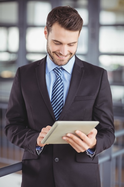 Bel homme d'affaires souriant tout en regardant une tablette numérique