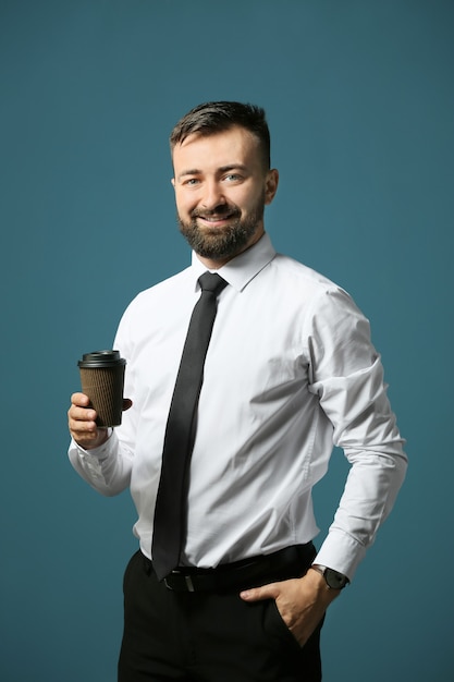 Bel homme d'affaires avec une tasse de café sur la couleur