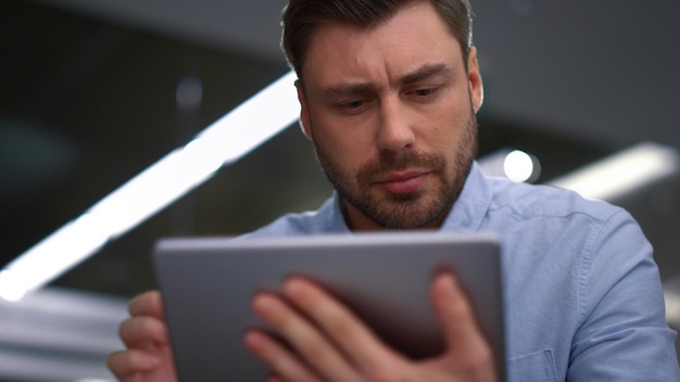 Bel homme d'affaires travaillant sur une tablette à la recherche d'informations financières dans le bureau de l'entreprise