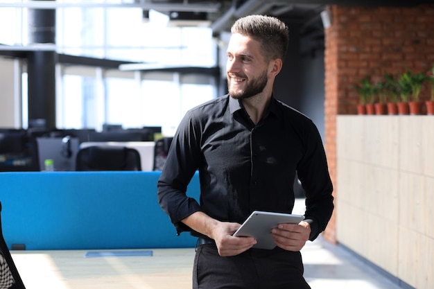 Bel homme d'affaires utilisant sa tablette au bureau.