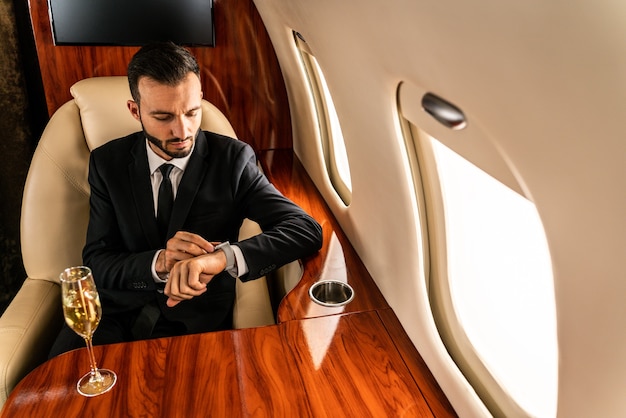 Bel homme d'affaires vêtu d'un costume élégant volant sur jet privé exclusif