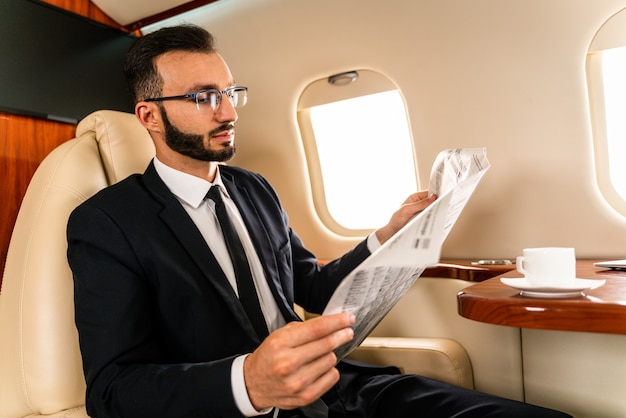 Bel homme d'affaires vêtu d'un costume élégant volant sur jet privé exclusif