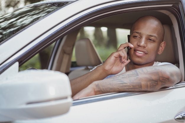 Bel homme africain, appréciant voyager en voiture sur un roadtrip