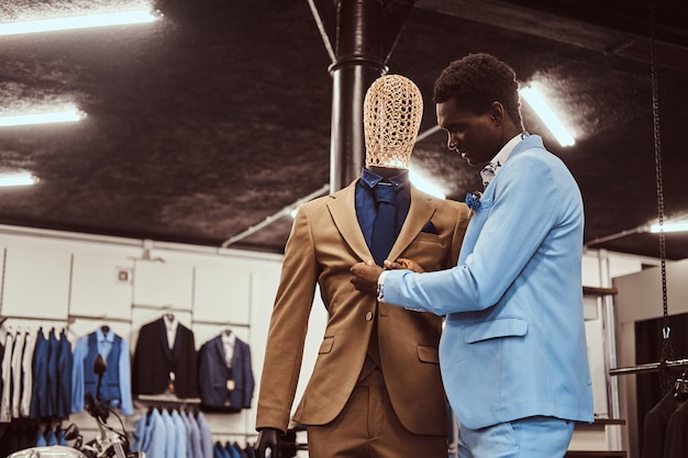 Bel homme afro-américain élégamment habillé travaillant dans un magasin de vêtements pour hommes classique.