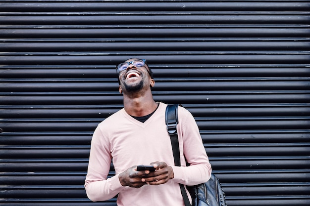 Bel homme afro-américain souriant avec smartphone