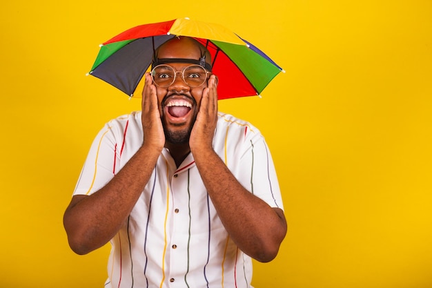 Bel homme afro brésilien habillé pour le carnaval fête brésilienne typique carnaval fête avec ses mains sur son visage surpris surpris étonnement bonheur joie incroyable wow