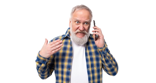 Bel homme âgé aux cheveux gris avec une barbe parle au téléphone sur un fond blanc