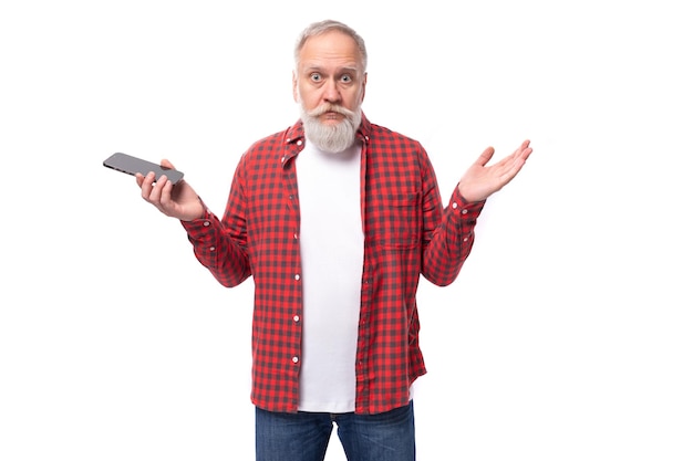 Bel homme âgé avec une barbe grise lève les mains tenant un téléphone