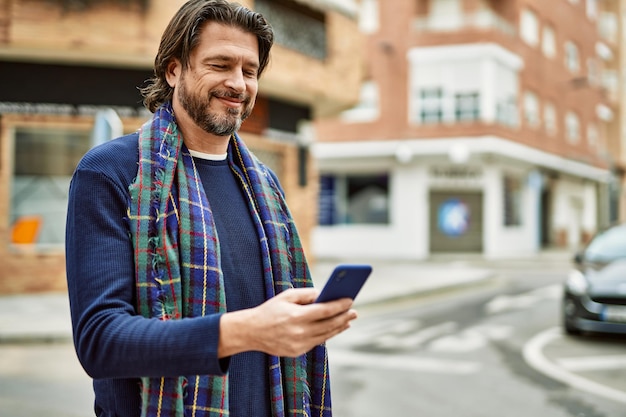 Bel homme d'âge moyen à l'aide de smartphone à la ville