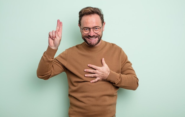 Bel homme d'âge moyen à l'air heureux confiant et digne de confiance souriant et montrant le signe de la victoire avec une attitude positive