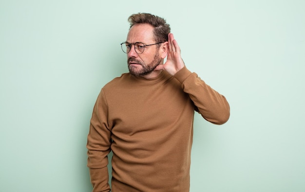 Photo bel homme d'âge moyen ayant l'air sérieux et curieux, écoutant, essayant d'entendre une conversation secrète ou des potins, écoutant