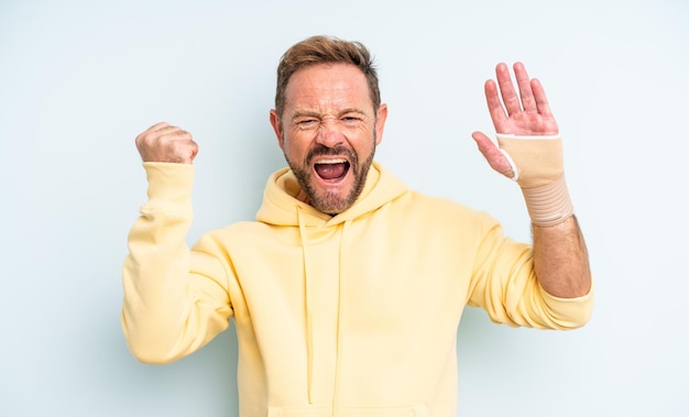 Bel homme d'âge moyen criant agressivement avec une expression de colère. notion de main cassée