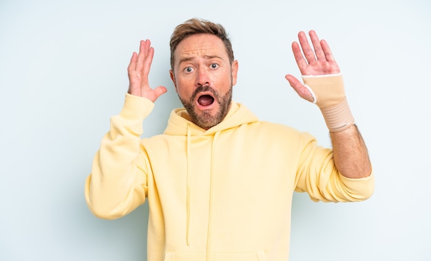 Bel homme d'âge moyen criant avec les mains en l'air. concept de main cassée