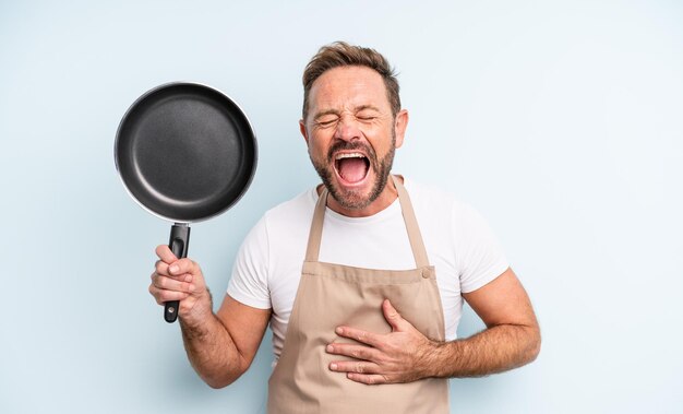 Bel homme d'âge moyen riant aux éclats d'une blague hilarante. concept de poêle à frire