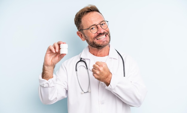 Bel homme d'âge moyen se sentant heureux et faisant face à un défi ou célébrant. médecin avec bouteille de pilules