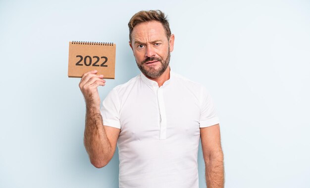 Bel homme d'âge moyen se sentant perplexe et confus. concept de calendrier 2022