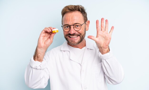 Bel homme d'âge moyen souriant et sympathique, montrant le numéro cinq. concept de lentilles de contact