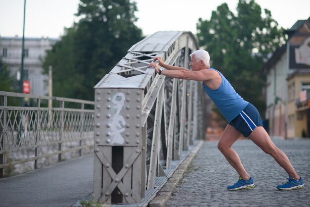 bel homme âgé qui s'étire et s'échauffe avant de faire de l'exercice de jogging tôt le matin