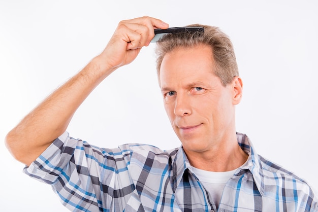 Bel homme âgé vif se peignant les cheveux