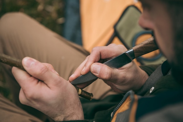 Bel homme aiguisant une branche pour le camping