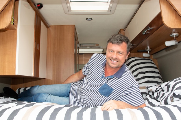 Bel homme allongé dans un lit de camping-car dans un camping-car en vacances jour RV