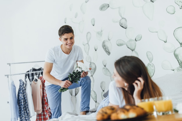 Un bel homme a apporté des fleurs dans le lit à sa femme.