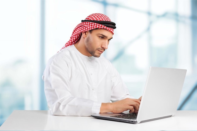 Bel homme arabe travaillant avec un ordinateur portable au bureau