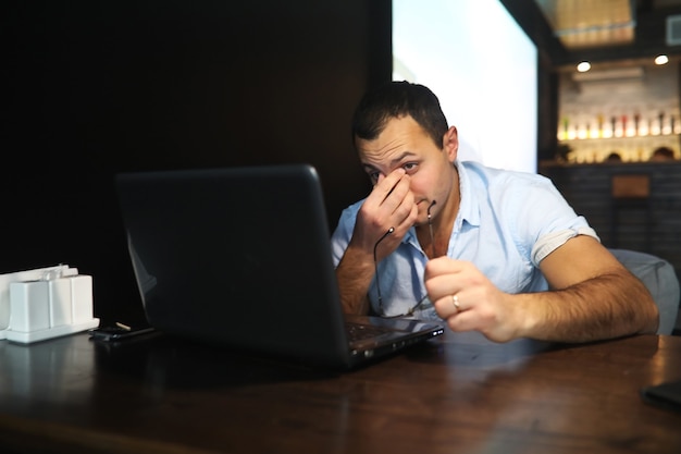 Bel homme arménien travaillant derrière un ordinateur portable dans un café