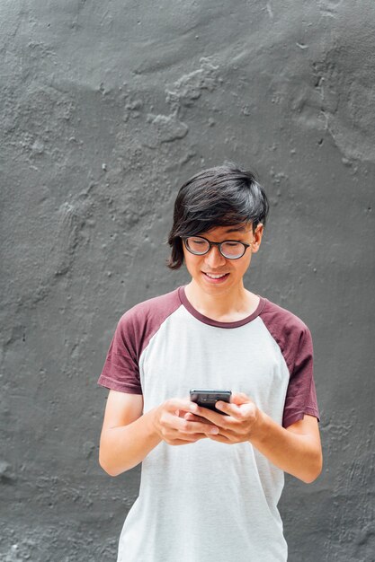 Bel homme asiatique à l'aide du mobile dans la rue. Concept de mode de vie.