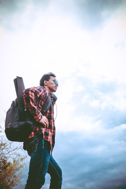 Bel homme asiatique au sommet de la montagne avec la plupart des nuages fond ton vintage