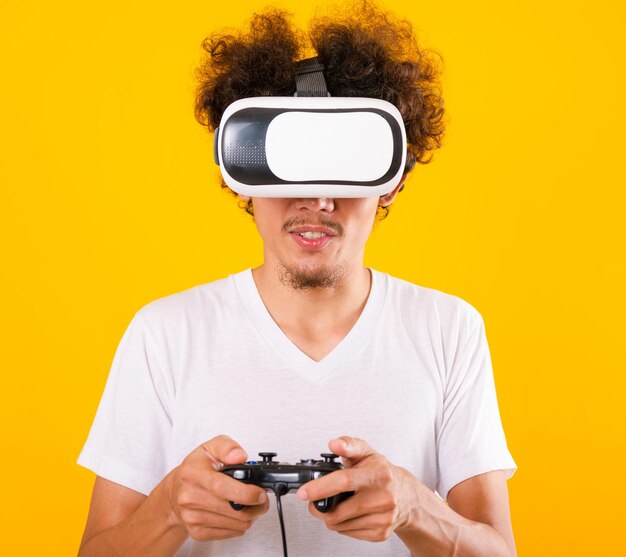 Bel homme asiatique aux cheveux bouclés jouer au jeu, il utilise un casque de réalité virtuelle ou un verre VR