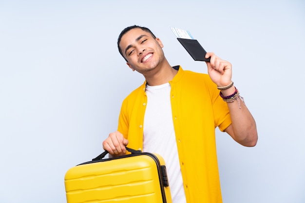 Bel homme asiatique isolé sur fond bleu en vacances avec valise et passeport
