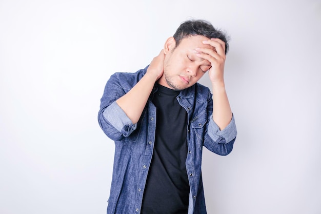 Bel homme asiatique souffrant de maux de tête debout sur fond blanc isolé