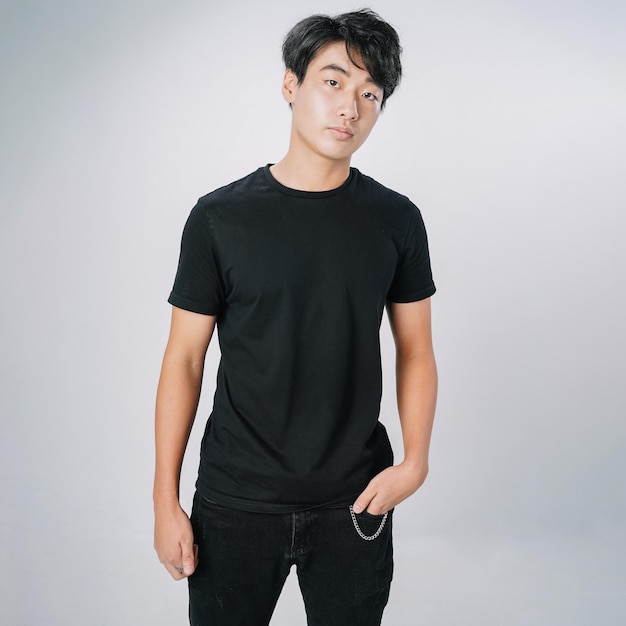 Bel homme asiatique tshirt noir sérieux debout mur gris isolé