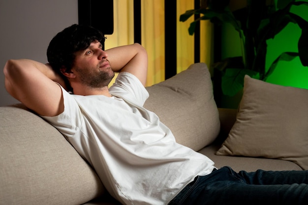 Bel homme assis sur un canapé dans un appartement élégant, soulagé après le travail, l'homme jette son
