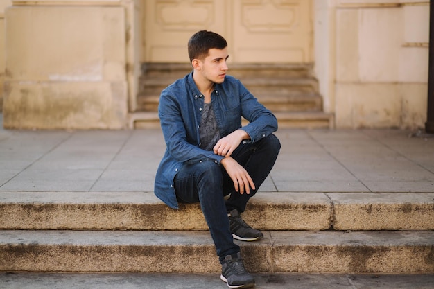 Photo bel homme assis dans les escaliers près du parc