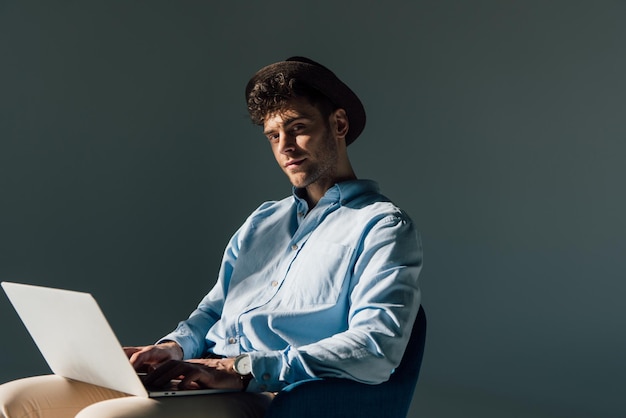 Bel homme assis avec un ordinateur portable au soleil et regardant la caméra