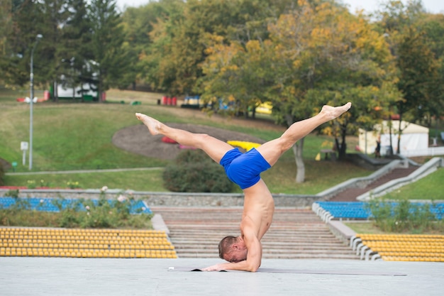 Bel homme athlétique faisant des asanas de yoga dans le parc