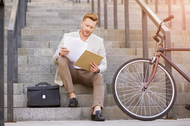 Bel homme attentif en costume élégant regardant à travers les contrats