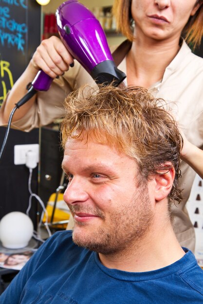 Bel homme au coup de coiffeur séchant ses cheveux