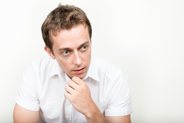 Bel homme aux cheveux bruns contre le mur blanc