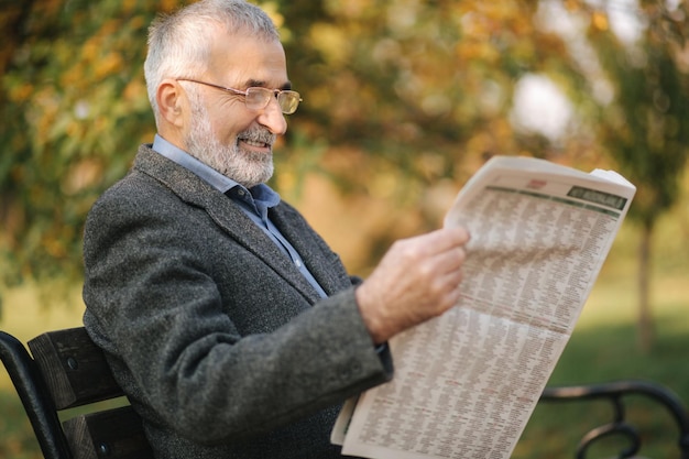 Bel homme aux cheveux gris assis sur le banc tôt le matin