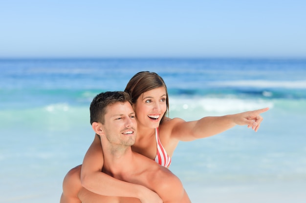 Bel homme ayant une femme un piggyback sur la plage