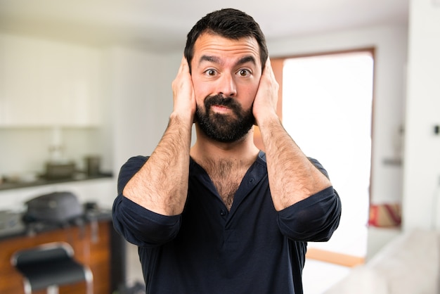 Bel homme avec barbe couvrant ses oreilles dans la maison