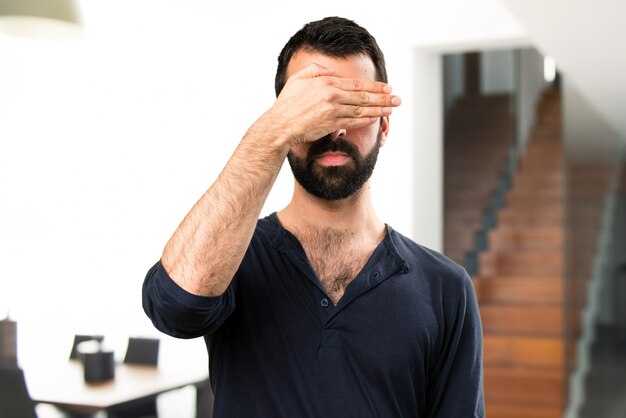 Bel homme avec barbe couvrant ses yeux dans la maison