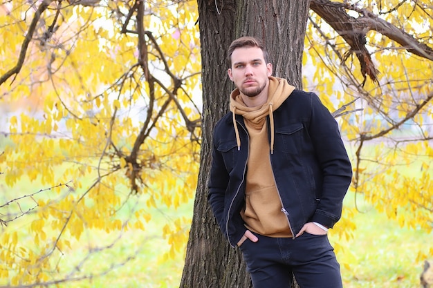 Bel homme à barbe dans le parc en automne se présentant à la caméra